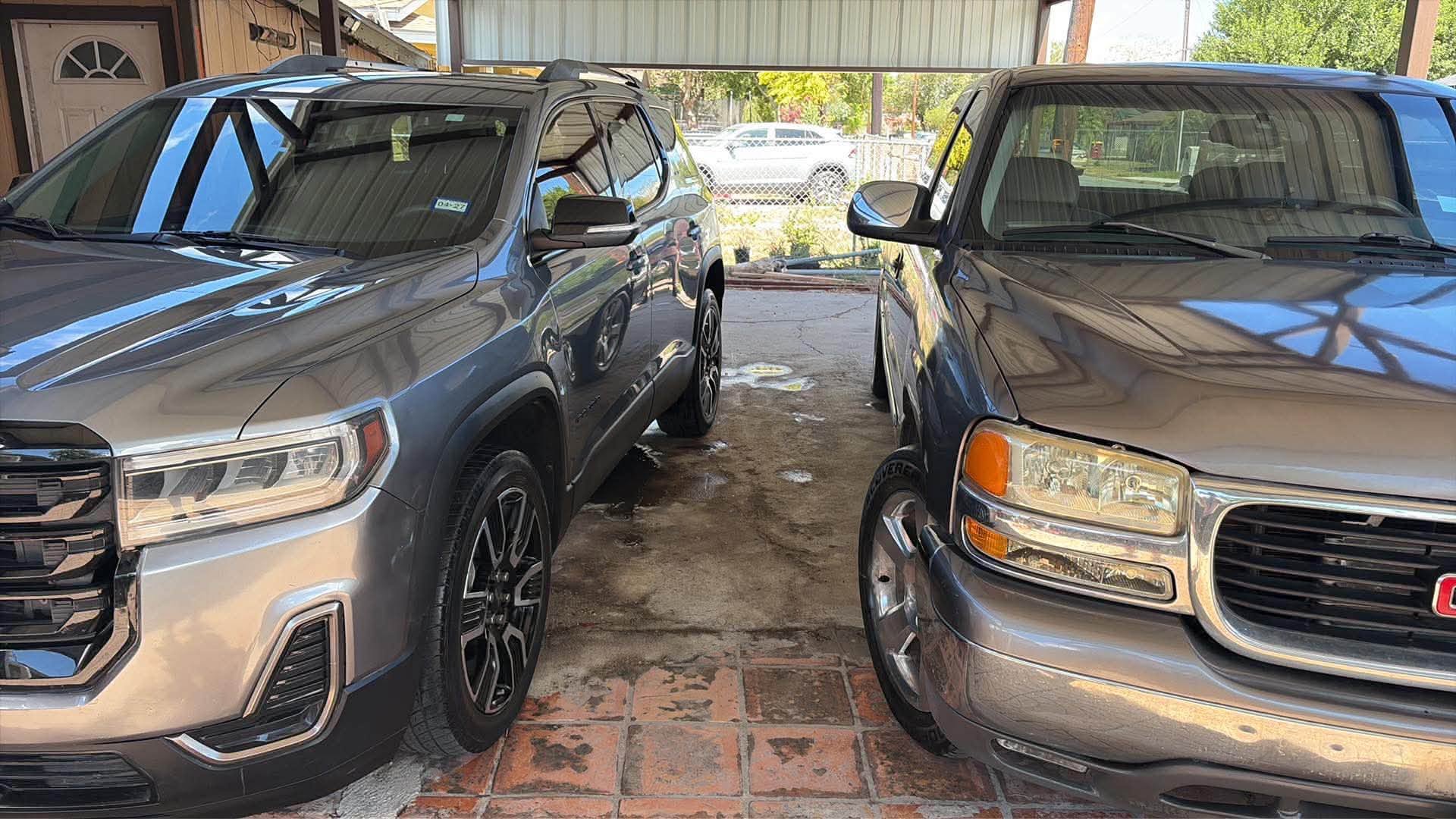 Two GMC vehicles washed side by side under a carport